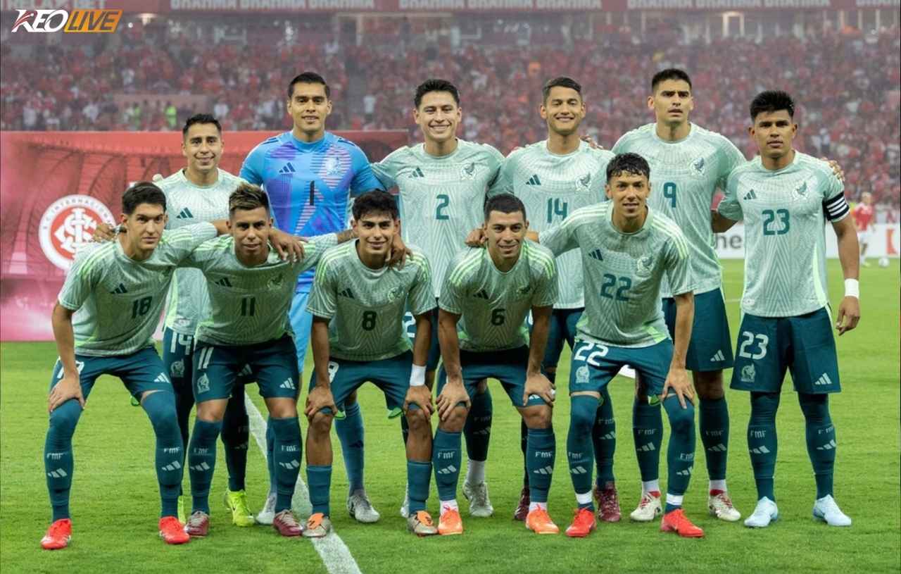 Đội tuyển Mexico bước vào World Cup 2026 với tư cách là một trong những đại diện giàu truyền thống nhất khu vực CONCACAF, đồng thời là đội tuyển có lịch sử ổn định bậc nhất tại các kỳ World Cup. Dưới sự dẫn dắt của HLV Javier Aguirre, Mexico tiếp tục duy trì hình ảnh của một tập thể giàu kinh nghiệm, tổ chức tốt và luôn biết cách cạnh tranh trong các trận đấu lớn. Tuy nhiên, trong bối cảnh bóng đá thế giới ngày càng khắc nghiệt, “El Tri” không còn được xem là đội bóng có khả năng tiến sâu, mà đang đứng trước bài toán làm mới lực lượng và nâng tầm chất lượng để vượt qua giới hạn quen thuộc. Mexico trước bài toán chưa có lời giải tại vòng 16 đội Mexico là một trong những đội tuyển có thành tích ổn định nhất tại World Cup. Trong suốt nhiều thập kỷ, họ gần như luôn vượt qua vòng bảng và góp mặt ở vòng 16 đội. Tuy nhiên, nghịch lý lớn nhất nằm ở chỗ họ chưa thể tiến xa hơn. Chuỗi dừng bước liên tiếp tại vòng knock-out đầu tiên đã trở thành một “giới hạn vô hình” mà Mexico chưa thể phá vỡ. Dù từng tổ chức World Cup và sở hữu nền bóng đá phát triển trong khu vực, Mexico vẫn thiếu những bước đột phá mang tính lịch sử. World Cup 2026, diễn ra trên sân nhà và khu vực Bắc Mỹ, sẽ là cơ hội lớn để họ thay đổi câu chuyện quen thuộc này. Tại World Cup 2026, Mexico nhiều khả năng sẽ nằm trong nhóm đội có lợi thế nhất định nhờ kinh nghiệm thi đấu và sự quen thuộc với môi trường. So với nhiều đối thủ, họ không vượt trội về chất lượng cá nhân, nhưng sở hữu bản lĩnh và sự lì lợm đáng kể. Việc vượt qua vòng bảng vẫn là mục tiêu khả thi, nhưng để tiến xa hơn, Mexico cần cải thiện khả năng tạo đột biến trong các trận đấu then chốt.   Triết lý của Javier Aguirre thiên về sự cân bằng và thực dụng. Mexico thường vận hành với sơ đồ 4-3-3 hoặc 4-2-3-1, chú trọng kiểm soát bóng ở mức vừa phải và tổ chức pressing có chọn lọc. Họ không phải đội pressing tầm cao liên tục, mà ưu tiên giữ cấu trúc đội hình và khai thác sai lầm của đối phương. Khả năng chuyển trạng thái của Mexico tương đối ổn định, nhưng thiếu tốc độ và độ sắc bén để trở thành vũ khí thực sự nguy hiểm trước các đội mạnh. Một tập thể giàu kinh nghiệm nhưng thiếu đột phá Điểm mạnh lớn nhất của Mexico nằm ở kinh nghiệm thi đấu quốc tế và sự gắn kết. Họ có nhiều cầu thủ đã quen với áp lực tại các giải đấu lớn, đặc biệt là World Cup. Tuy nhiên, hạn chế rõ ràng nằm ở việc thiếu những cá nhân có khả năng tạo khác biệt ở đẳng cấp cao nhất. Mexico không phải là đội bóng dễ bị đánh bại, nhưng cũng không phải tập thể có thể áp đặt thế trận trước các đối thủ mạnh. Điều này khiến họ thường rơi vào trạng thái “đủ tốt để cạnh tranh, nhưng chưa đủ để bứt phá”. Trong khung thành, Guillermo Ochoa vẫn là cái tên mang tính biểu tượng, dù đã bước sang giai đoạn cuối sự nghiệp. Kinh nghiệm và phản xạ của anh vẫn là điểm tựa lớn, nhưng yếu tố tuổi tác khiến Mexico cần chuẩn bị cho sự chuyển giao. Raúl Rangel và Carlos Acevedo là những phương án kế cận, mang lại sự ổn định nhất định nhưng chưa tạo ra sự khác biệt rõ ràng. Hàng phòng ngự của Mexico mang tính thực dụng và linh hoạt. Những cái tên như César Montes, Johan Vásquez hay Jorge Sánchez tạo nên một hệ thống tương đối chắc chắn. Ở hai cánh, Jesús Gallardo và Mateo Chávez hỗ trợ tấn công ở mức vừa phải, nhưng không phải mẫu hậu vệ biên tạo đột biến cao. Điểm mạnh của hàng thủ nằm ở tổ chức và kinh nghiệm, nhưng họ có thể gặp khó khi đối đầu với các đội bóng có tốc độ và khả năng pressing mạnh. Tuyến giữa Mexico là khu vực giàu năng lượng nhưng không quá sáng tạo. Edson Álvarez đóng vai trò mỏ neo với khả năng đánh chặn và hỗ trợ phòng ngự, trong khi Orbelín Pineda và Luis Chávez giúp duy trì nhịp độ trận đấu. Álvaro Fidalgo mang đến yếu tố kỹ thuật, nhưng nhìn chung Mexico vẫn thiếu một tiền vệ sáng tạo thực sự có thể thay đổi cục diện trận đấu. Khả năng kiểm soát bóng của Mexico ở mức ổn định, nhưng họ thường gặp khó trước các hệ thống pressing cường độ cao. Điều này khiến họ dễ rơi vào thế bị động khi đối đầu với các đội tuyển hàng đầu. Trên hàng công, Santiago Giménez là cái tên được kỳ vọng nhiều nhất. Tiền đạo này sở hữu khả năng dứt điểm tốt và di chuyển thông minh, nhưng vẫn cần chứng minh khả năng tỏa sáng ở sân chơi lớn. Raúl Jiménez mang đến kinh nghiệm, trong khi Alexis Vega và Julián Quiñones hỗ trợ ở hai cánh. Tuy nhiên, vấn đề của Mexico nằm ở chỗ họ không có một cầu thủ có thể tạo đột biến liên tục. Hàng công của họ phụ thuộc nhiều vào hệ thống, thay vì những khoảnh khắc cá nhân. Đây sẽ là kỳ World Cup cuối của Ochoa World Cup 2026 sẽ là lần cuối Guillermo Ochoa góp mặt trong màu áo đội tuyển quốc gia. Thủ môn này đã trở thành biểu tượng của Mexico qua nhiều kỳ World Cup với những màn trình diễn xuất sắc. Dù không còn ở đỉnh cao phong độ, Ochoa vẫn mang lại giá trị lớn về kinh nghiệm và tinh thần. Anh là cầu nối giữa các thế hệ, đồng thời là điểm tựa tâm lý cho toàn đội. Tuy nhiên, Mexico cũng cần chuẩn bị cho tương lai khi không còn sự phục vụ của thủ thành kỳ cựu này. Xét về cơ hội tại World Cup 2026, Mexico vẫn có khả năng vượt qua vòng bảng nhờ kinh nghiệm và sự ổn định. Tuy nhiên, mục tiêu vượt qua vòng 16 đội vẫn là thách thức lớn. Điểm mạnh của họ nằm ở tổ chức, bản lĩnh và khả năng thi đấu trong môi trường áp lực cao. Ngược lại, hạn chế lớn nhất là thiếu những cá nhân có thể tạo đột biến và khả năng áp đặt thế trận trước các đội bóng mạnh. Đây chính là rào cản khiến Mexico nhiều năm liền không thể tiến xa hơn. Nhìn tổng thể, Mexico bước vào World Cup 2026 với hình ảnh quen thuộc: một đội bóng giàu kinh nghiệm, tổ chức tốt nhưng thiếu yếu tố bùng nổ. Lợi thế sân nhà và khu vực có thể giúp họ tiến sâu hơn kỳ vọng, nhưng để tạo ra bước ngoặt lịch sử, Mexico cần nhiều hơn là sự ổn định. Nếu không cải thiện được khả năng tạo khác biệt ở những trận đấu lớn, “El Tri” nhiều khả năng sẽ tiếp tục dừng bước ở vòng knock-out, kịch bản đã lặp lại trong suốt nhiều năm qua. Theo dõi keolive để cập nhật liên tục những tin tức mới nhất của bóng đá thế giới. | Keolive